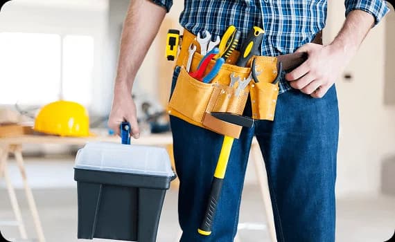 Maintenance engineer carrying a toolbox and wearing a tool belt