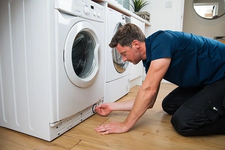 Appliance repair in London – engineer cleaning washing machine filter to fix drainage problem